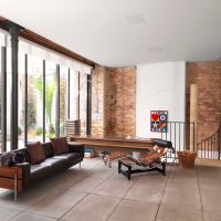 Loft-style living room with exposed brick walls, leather sofa, chaise lounge, and in-ceiling B&W speakers.