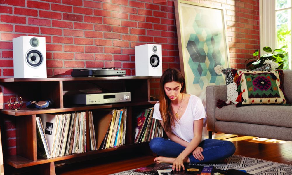 <span class="uk-h4">Woman looks through vinyl records while sitting on the floor in front of an AV stand</span>