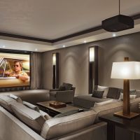 Luxurious home theater with cozy gray sectional seating, ambient lighting, and a large projector screen showing a movie.